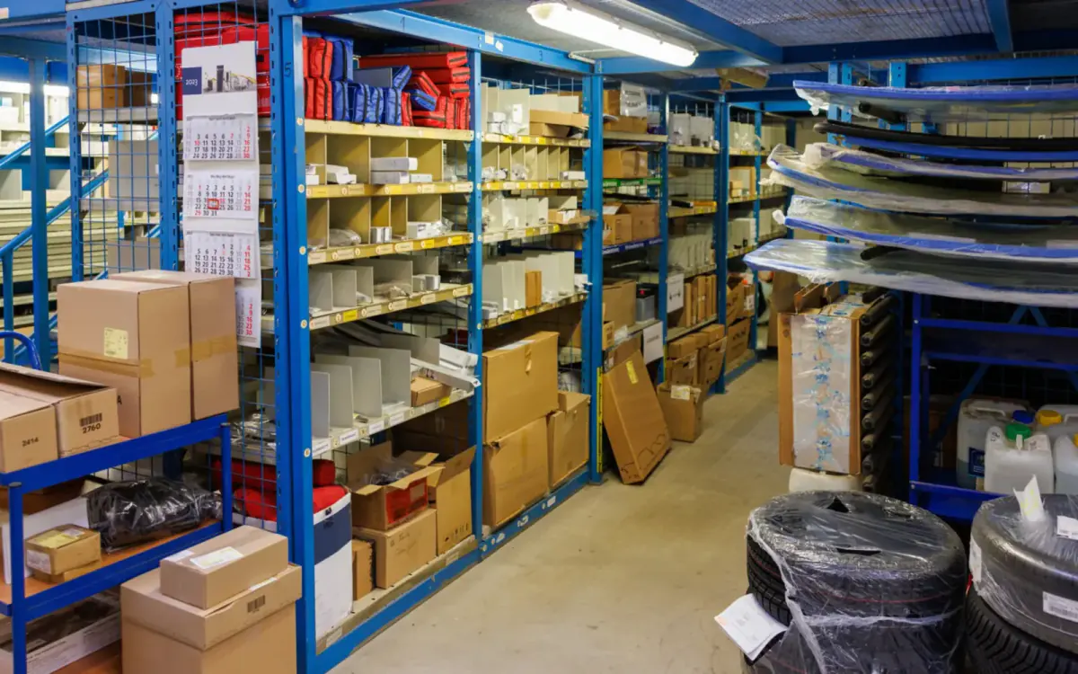 Auto parts warehouse shelves stacked with boxed used car parts — parting out a car vs. selling it whole